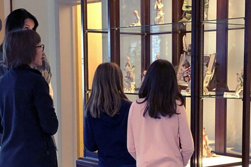A group of people observing a display case with figurines. 3