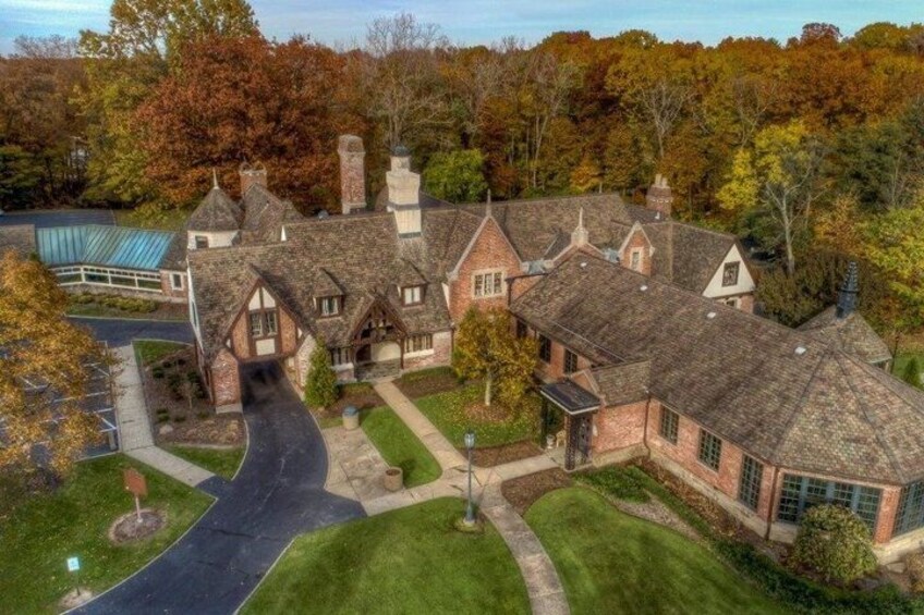 A large, multi-story house with a steeply pitched roof, surrounded by a well-maintained lawn and mature trees. 5