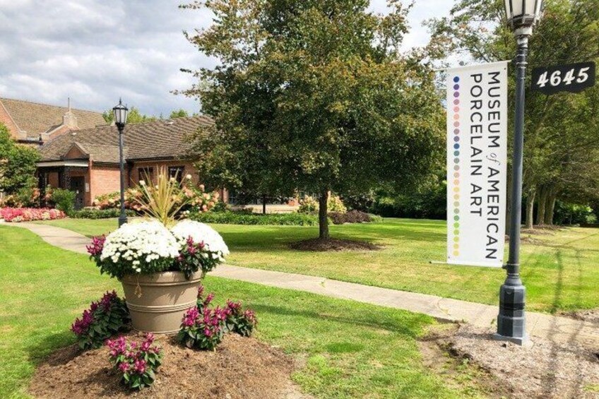 A sign for the Museum of American Porcelain Art, a landscaped garden with a pathway, and a building in the background. 4