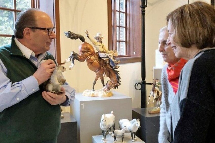 A person holding a small animal, a statue of a horse, and a sheep sculpture. 1