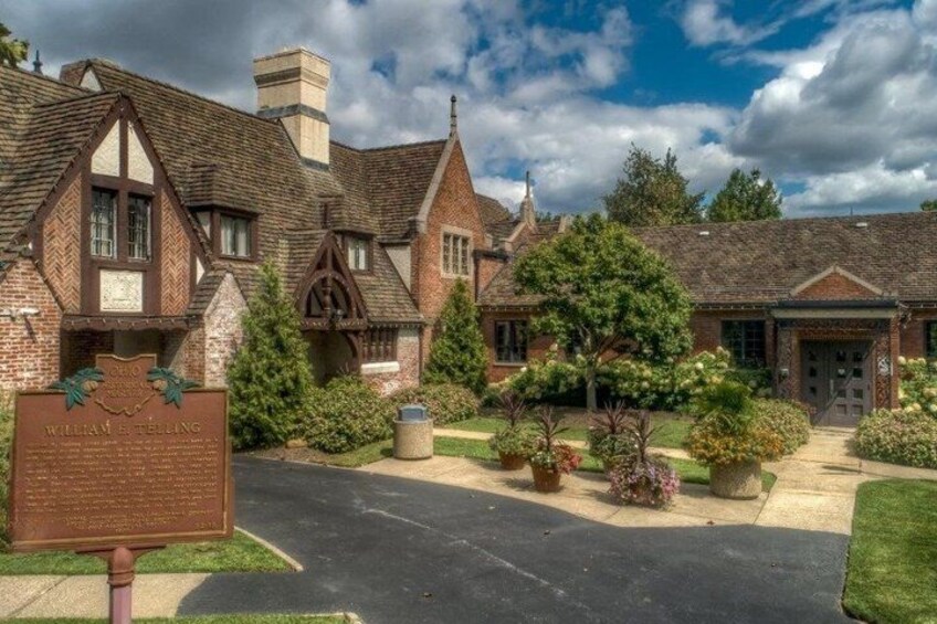 A historic building with Tudor-style architecture, a well-maintained lawn, and a clear sky. 2