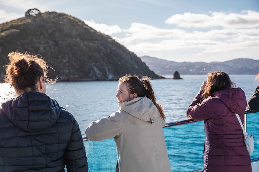 Tres personas en un bote, contemplando un paisaje costero con colinas y cielo despejado. 4