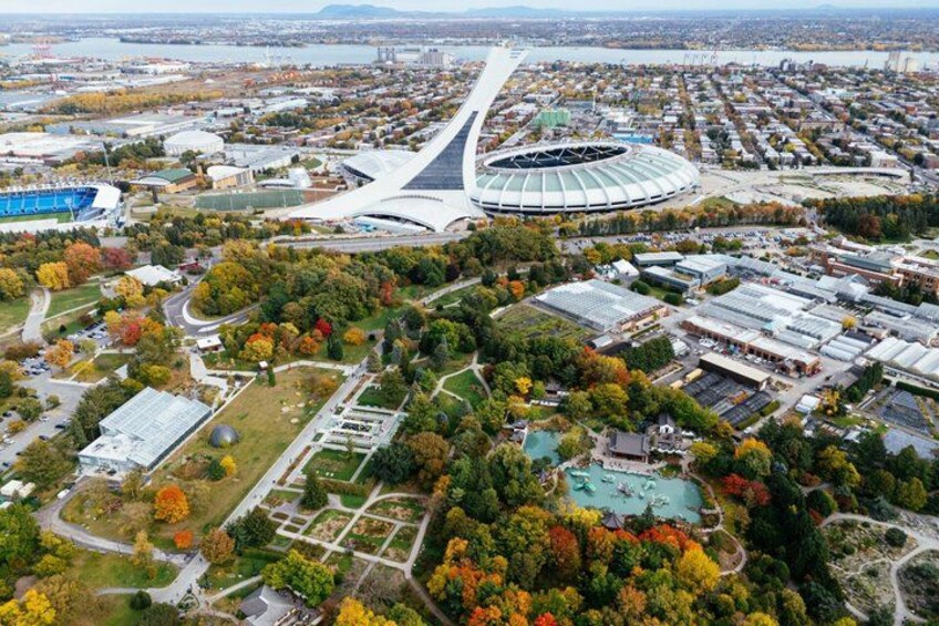 An aerial view of a city with a large stadium, surrounding greenery, and a river. 3