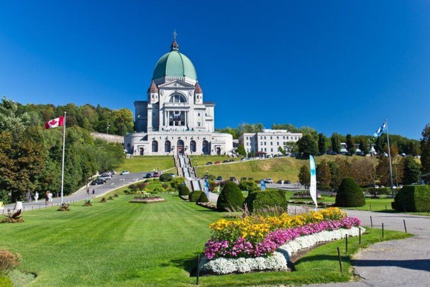 A large government building with a green dome, surrounded by well-maintained gardens and a clear blue sky. 1
