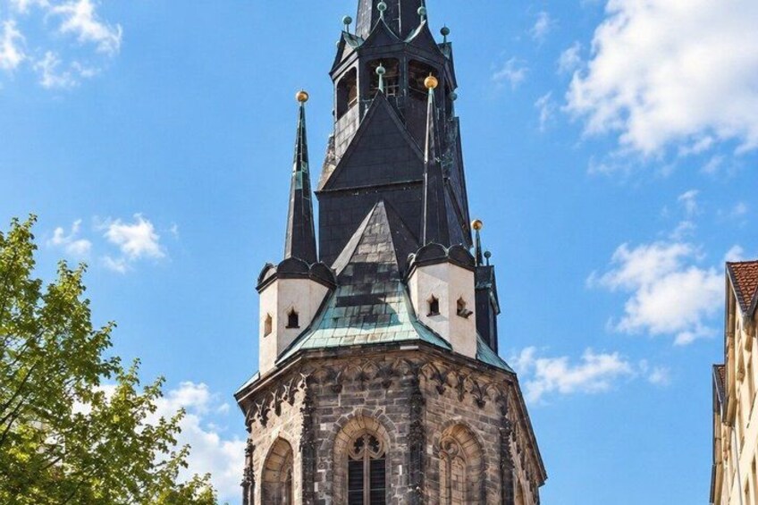 A church tower with a pointed spire, arched windows, and a clock. 4