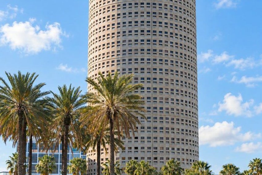 A tall, cylindrical building with a grid of windows, surrounded by palm trees. 5