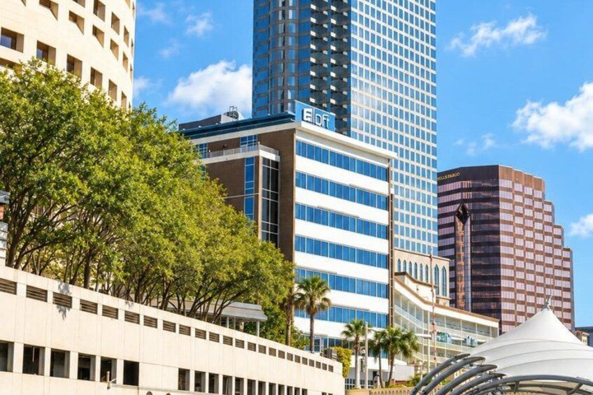 A cityscape with modern buildings, including a tall blue skyscraper and a white building with a curved roof. 2