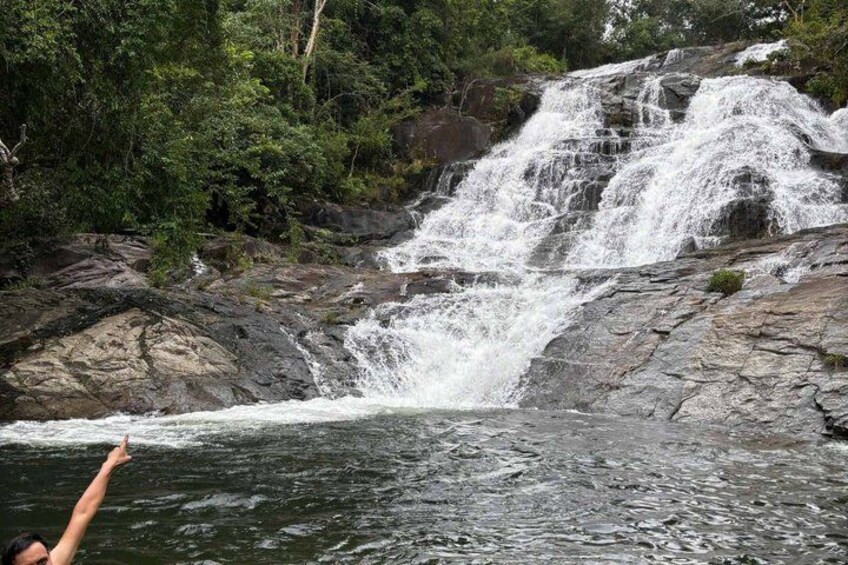 A waterfall cascading over rocks surrounded by dense greenery. 4