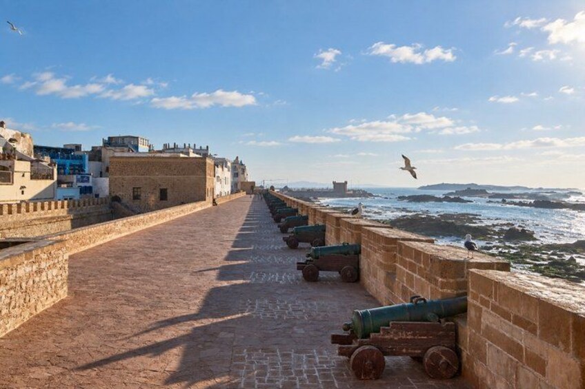 A coastal fortification with cannons, a clear sky, and the sea in the background. 2