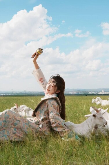 A person lying on the grass in a field with a goat nearby. 4
