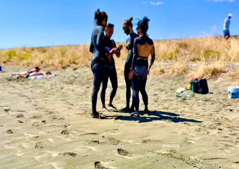 Una playa arenosa con huellas, una persona acostada en la arena y otra caminando al fondo. 2