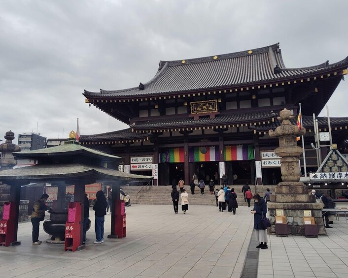 Un edificio japonés tradicional con techo de tejas y un monumento de piedra al frente. 5