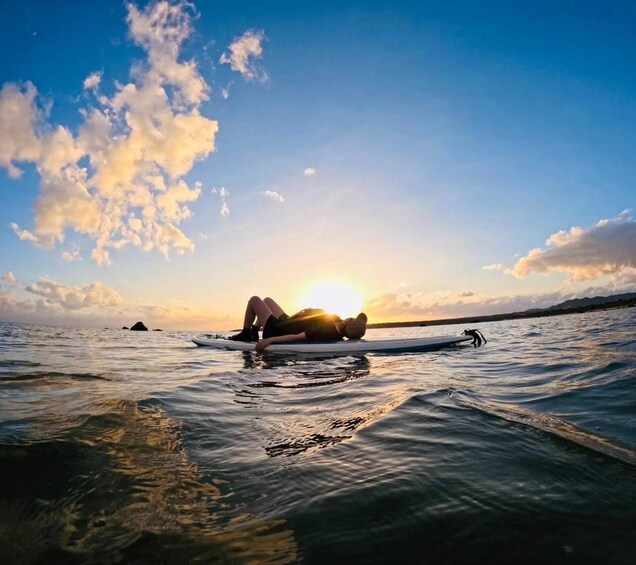 Una persona sdraiata su una tavola da surf nell'oceano al tramonto. 5