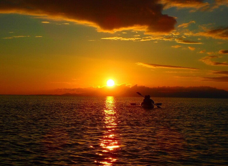 Tramonto sul mare calmo con persone che fanno kayak. 2