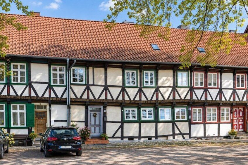 A traditional half-timbered house with a red-tiled roof, a parked car, and a bench in front. 2