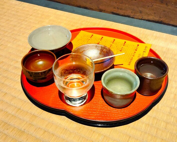 A tray with various bowls and a glass, possibly containing food and drink, on a wooden table. 1