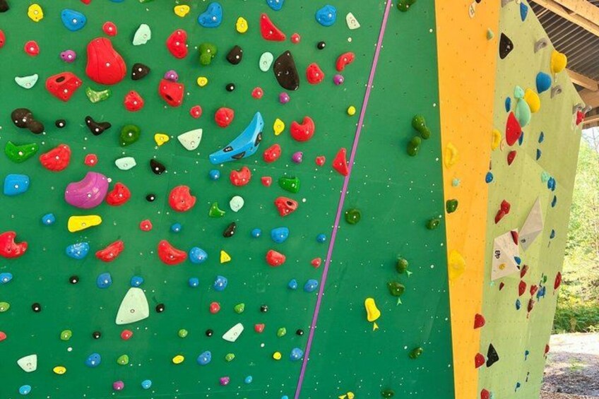 A climbing wall with colorful holds and a yellow safety line. 4