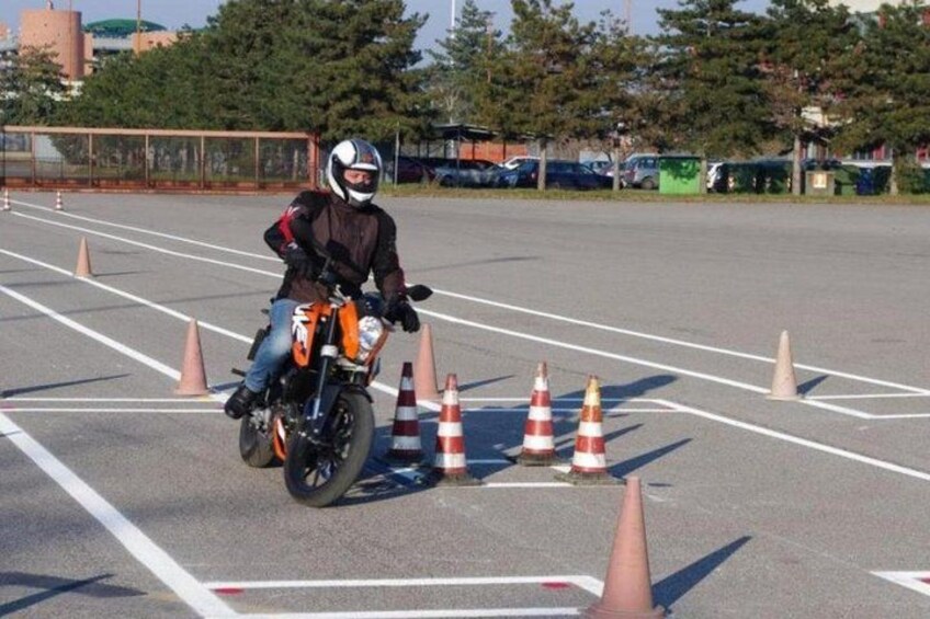 A person riding a motorcycle in a parking lot with traffic cones. 1