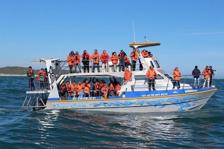 A boat with people in orange life jackets on the water. 2