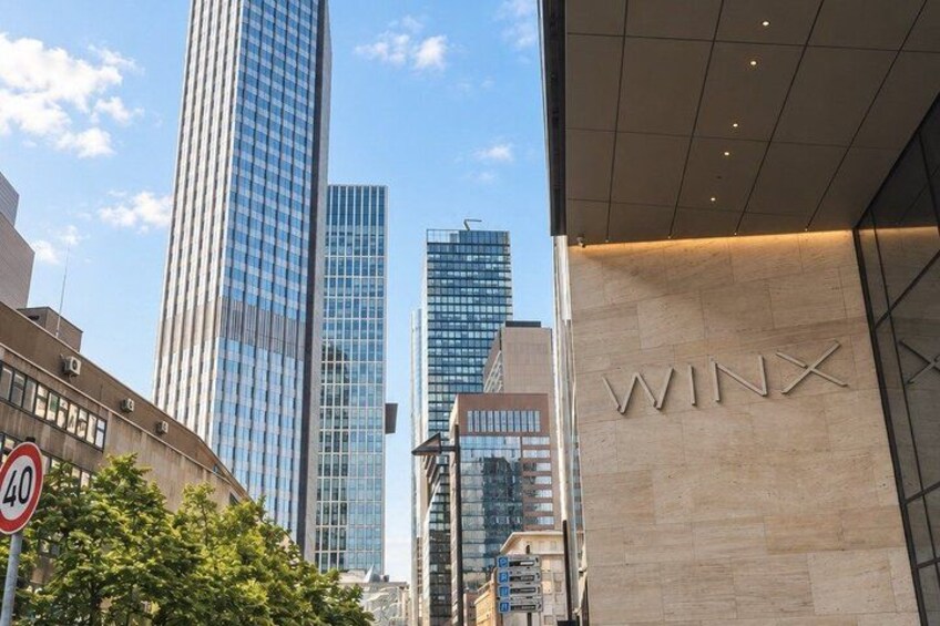 A cityscape with modern buildings, including a tall skyscraper and a building with the sign 'WINX'. 4