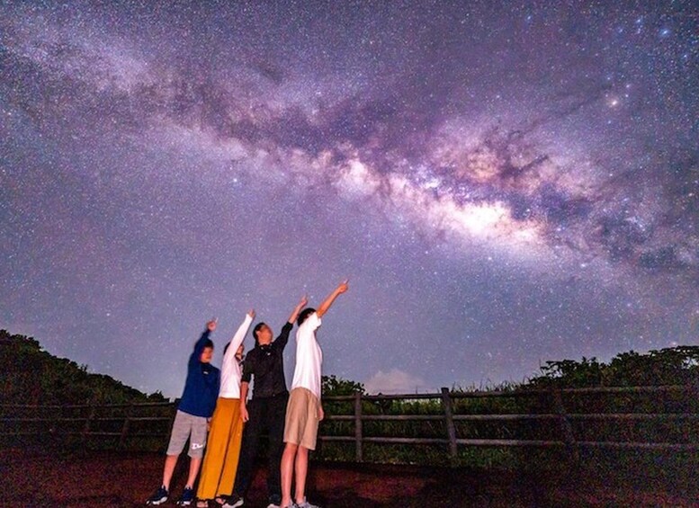 Un grupo de personas de pie al aire libre bajo un cielo estrellado, con la Vía Láctea visible. 1
