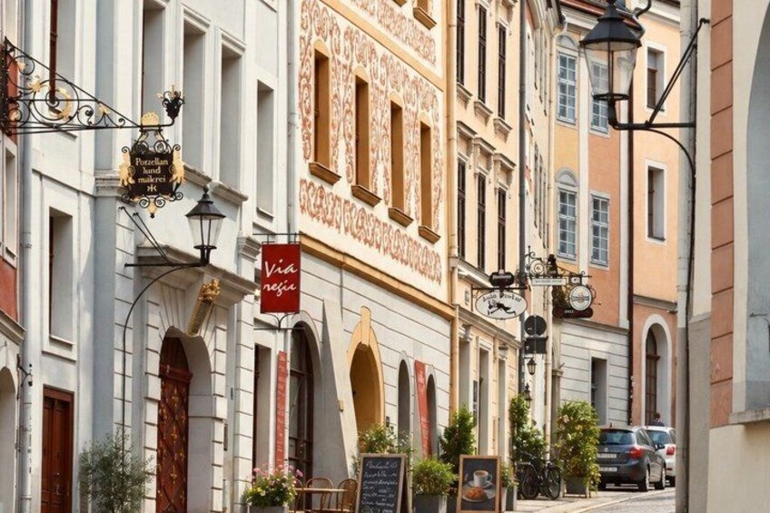 A street with buildings, a sign reading 'Via Neja,' and a parked bicycle. 3