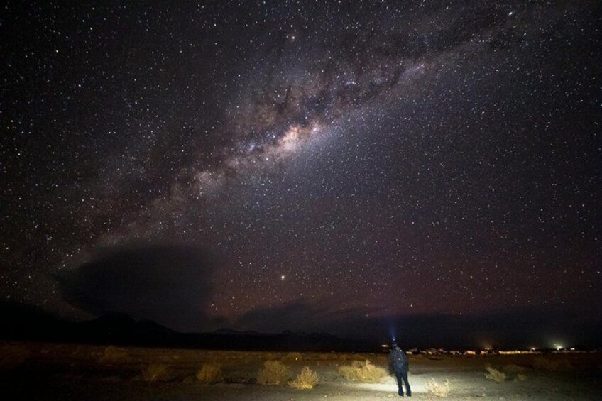A person standing under a starry night sky with the Milky Way visible. 1