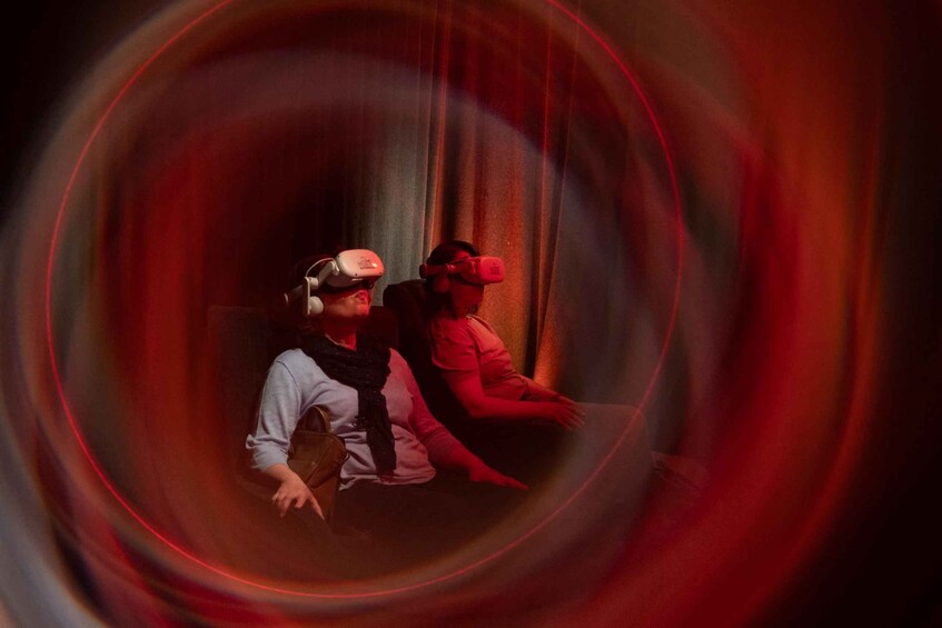Two people wearing VR headsets sitting in a room with red lighting. 5