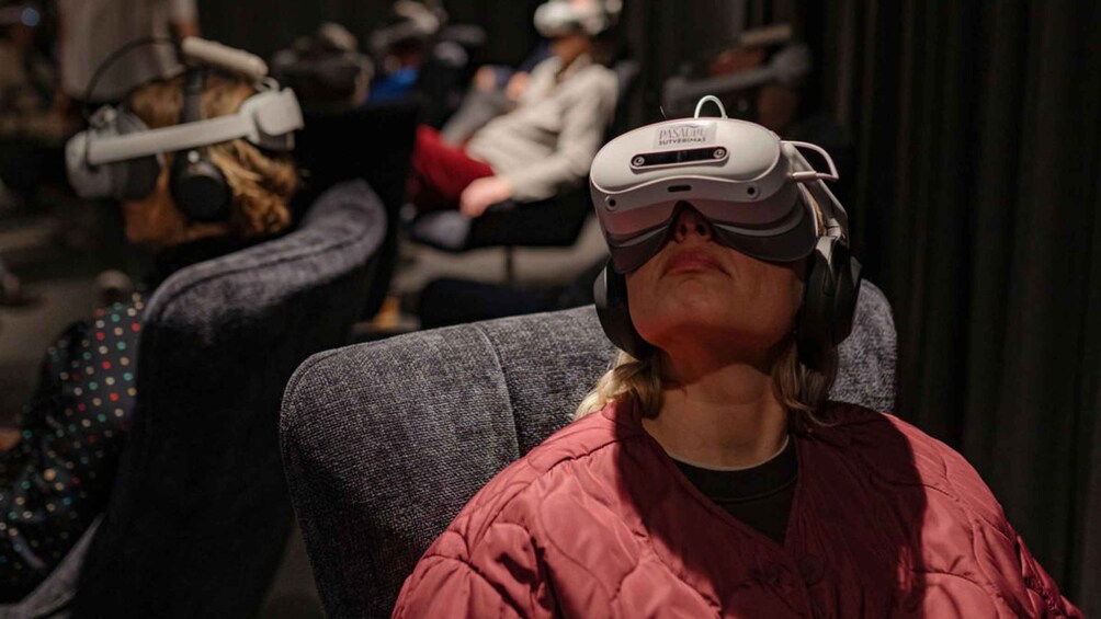 A person wearing a virtual reality headset seated in a public space. 2