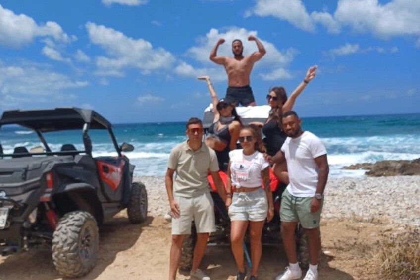 Un grupo de personas posando en una playa, cerca un buggy de arena estacionado. 5