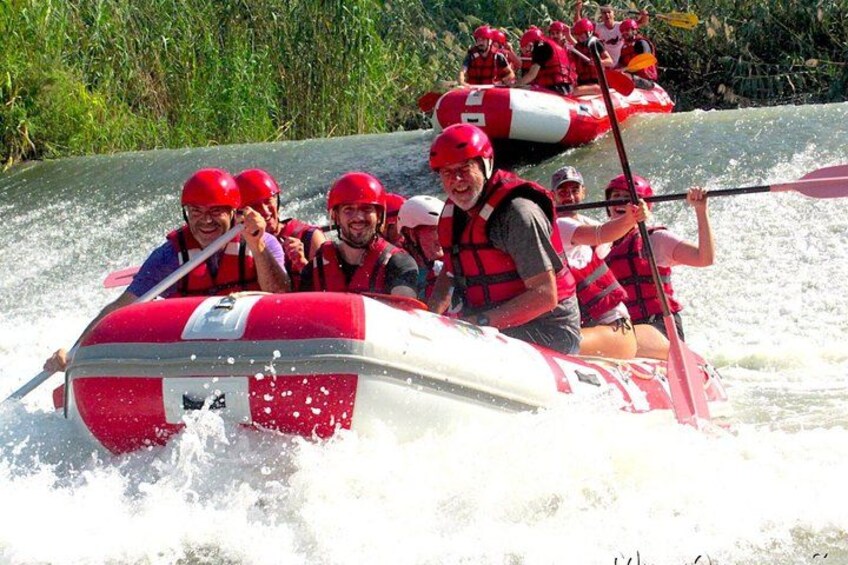 A group of people in a red and white raft navigating a river. 4
