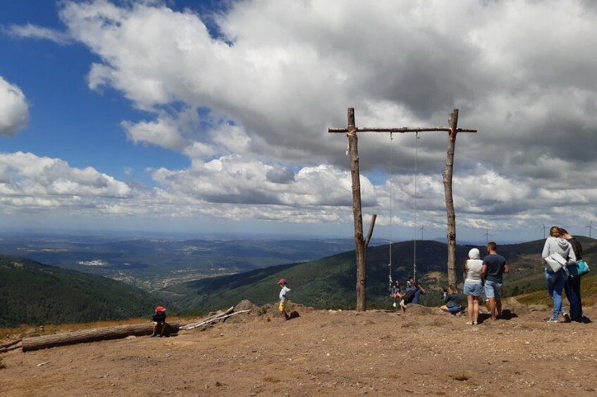 A mountainous landscape with a wooden swing set, people walking, and a clear sky. 4