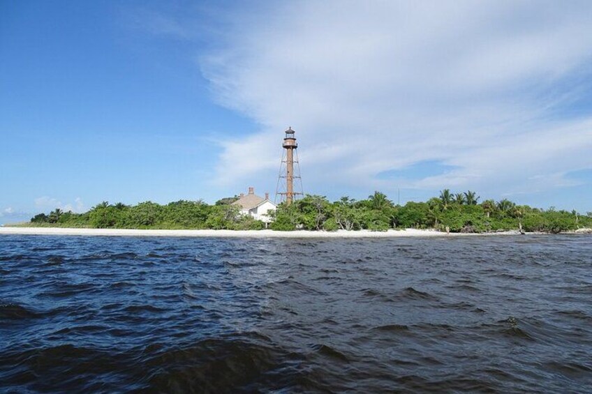A lighthouse on a small island with calm waters and a clear sky. 4