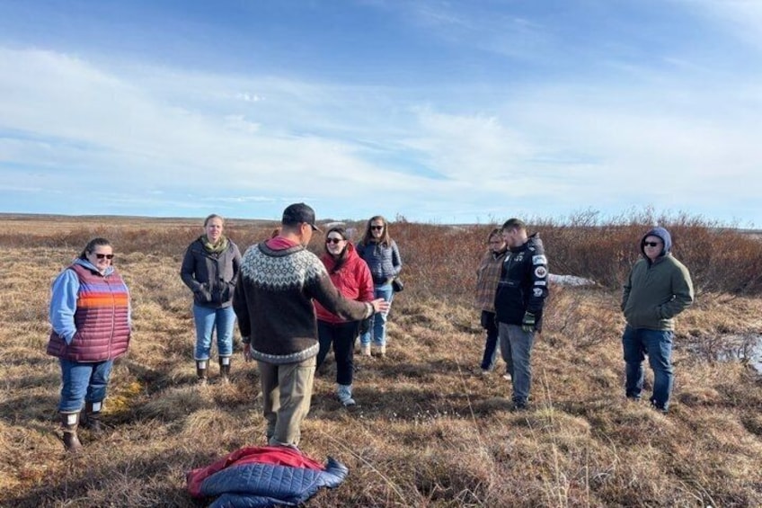 A group of people standing in a field with dry grass and a clear sky. 5