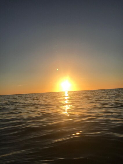Un atardecer sobre un mar tranquilo con el sol reflejado en el agua. 2