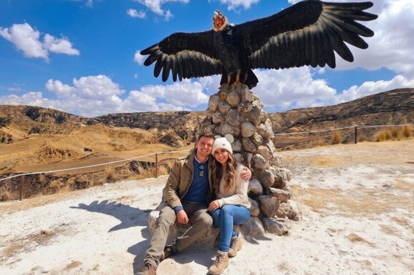 A couple sitting at a rock formation with an eagle statue above them. 3
