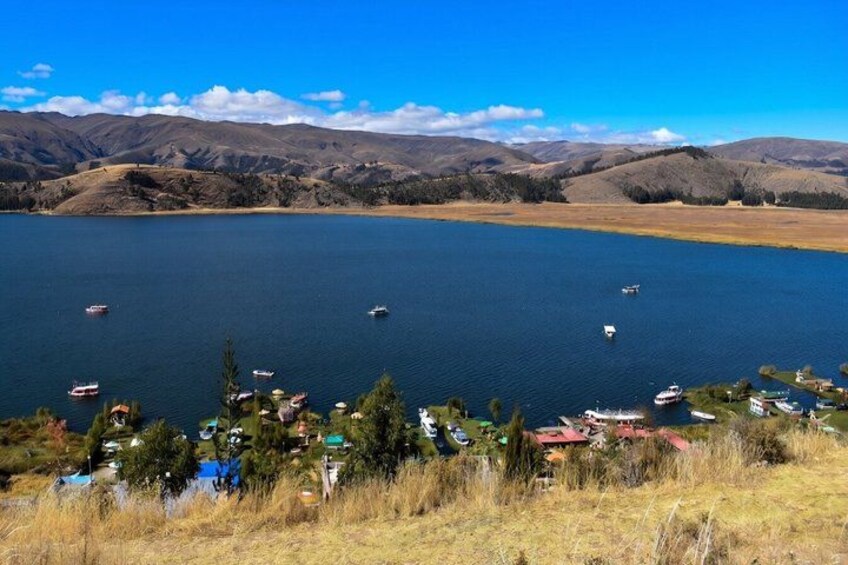 A lake with boats, a small settlement, and distant mountains. 1