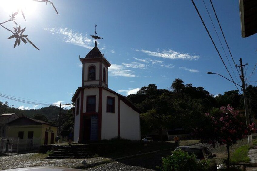 A small church with a bell tower, surrounded by greenery and a clear sky. 5