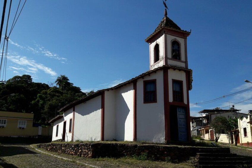 A small church with a bell tower, surrounded by a cobblestone path and residential buildings. 3
