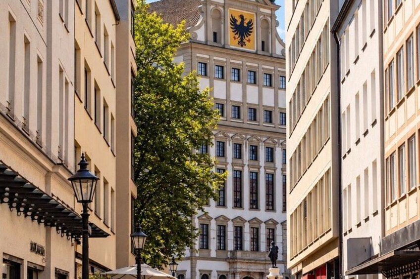 A building with a large eagle emblem, a tree, and a street lamp. 2