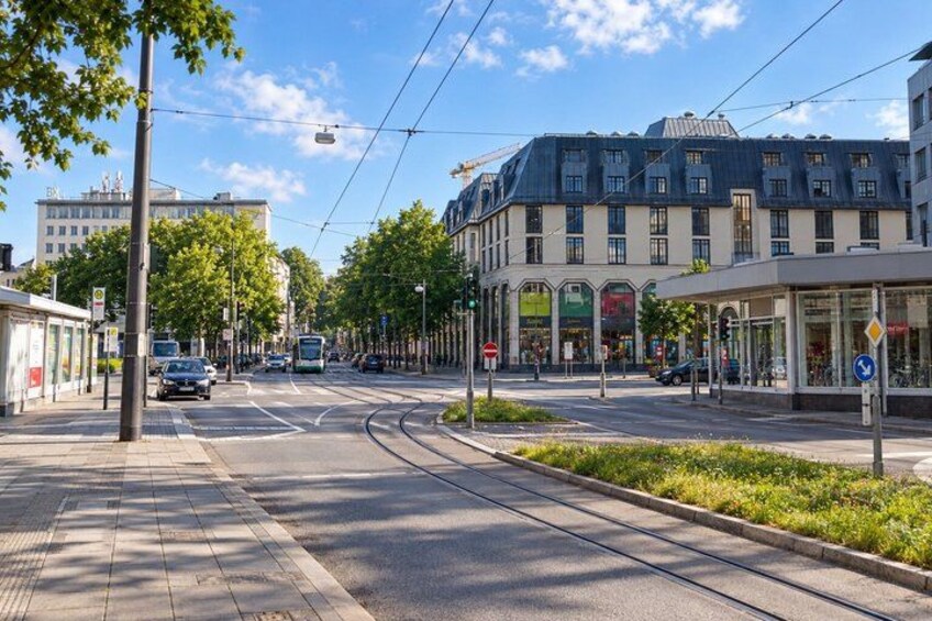A city street with tram tracks, buildings, and a tram in motion. 5