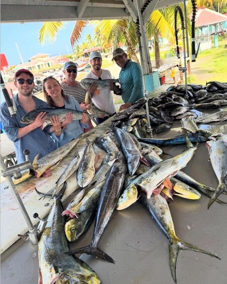 Un grupo de personas sosteniendo peces, con una gran exhibición de diversas especies de pescado sobre una mesa. 5