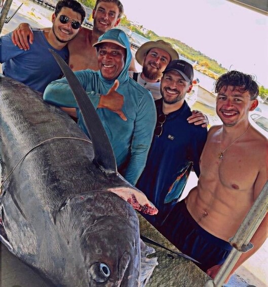Un grupo de personas posando con un pez grande en un bote. 4