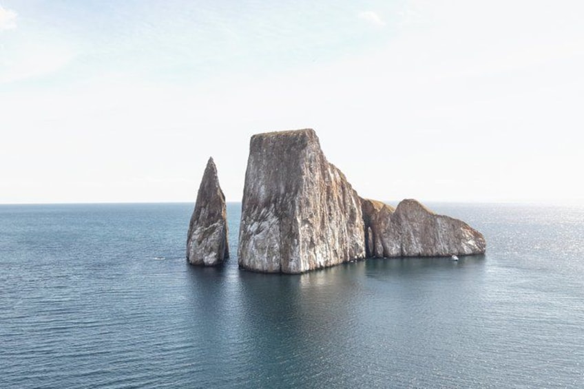 A large rock formation in the sea with a clear sky. 1