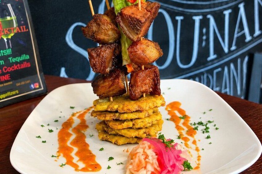 A plate of food with skewers of meat and fried plantains, garnished with herbs and a sauce. 2