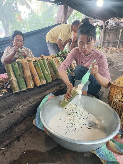 People processing bamboo, a large metal bowl, and a makeshift shelter. 4