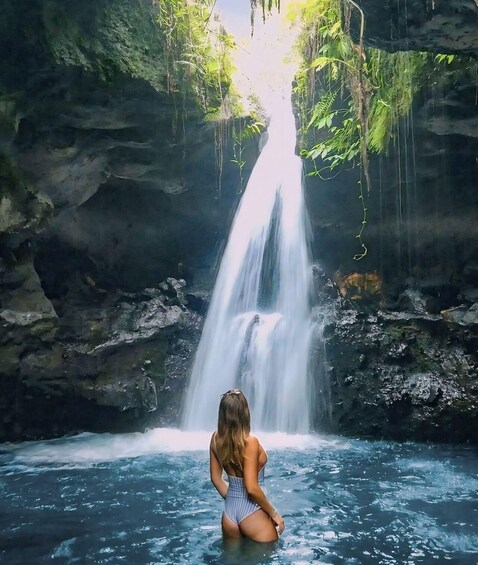 Una cascada en un desfiladero rocoso con una persona de pie en el agua. 4