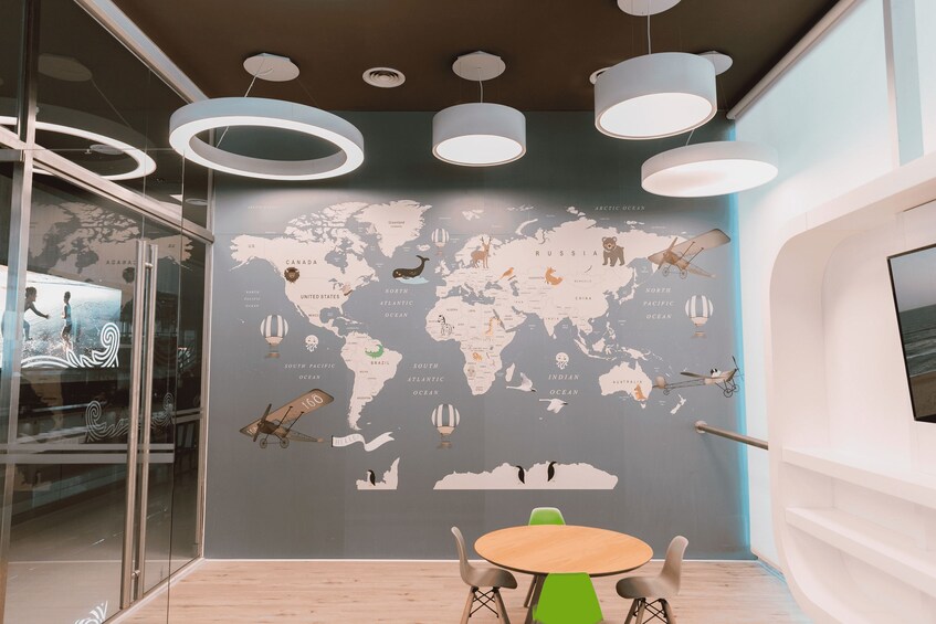 A modern interior with a world map mural, a round table, and hanging lights. 5
