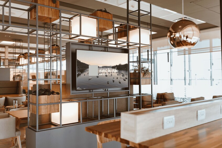 A modern interior with a large TV screen displaying a scenic landscape, surrounded by wooden furniture and shelves. 1