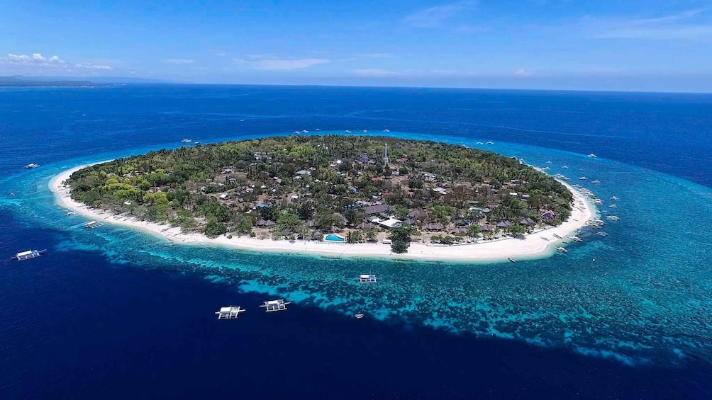 Vue aérienne d’une île tropicale aux eaux turquoise et limpides, bordée d’une plage de sable et couverte d’une végétation luxuriante. 2
